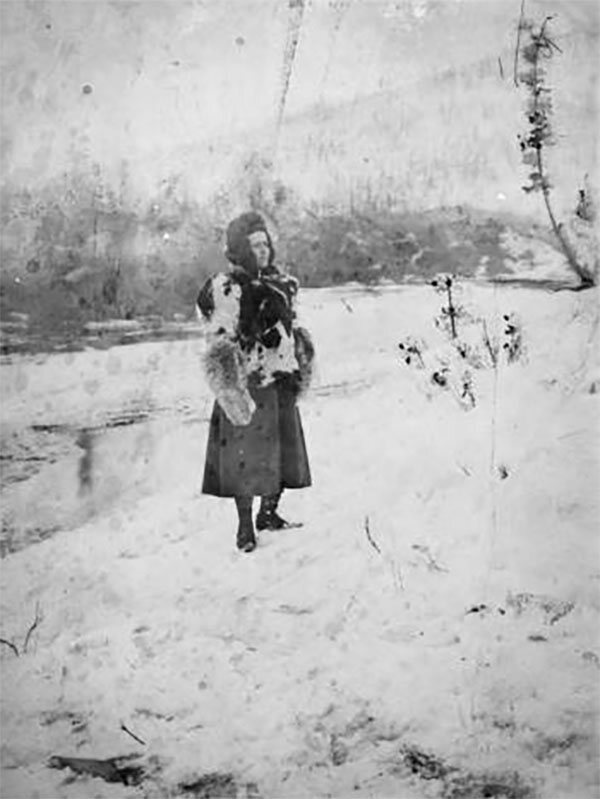 Fannie Quigley in Alaska, standing in the snow wearing a skirt and a fur parka.