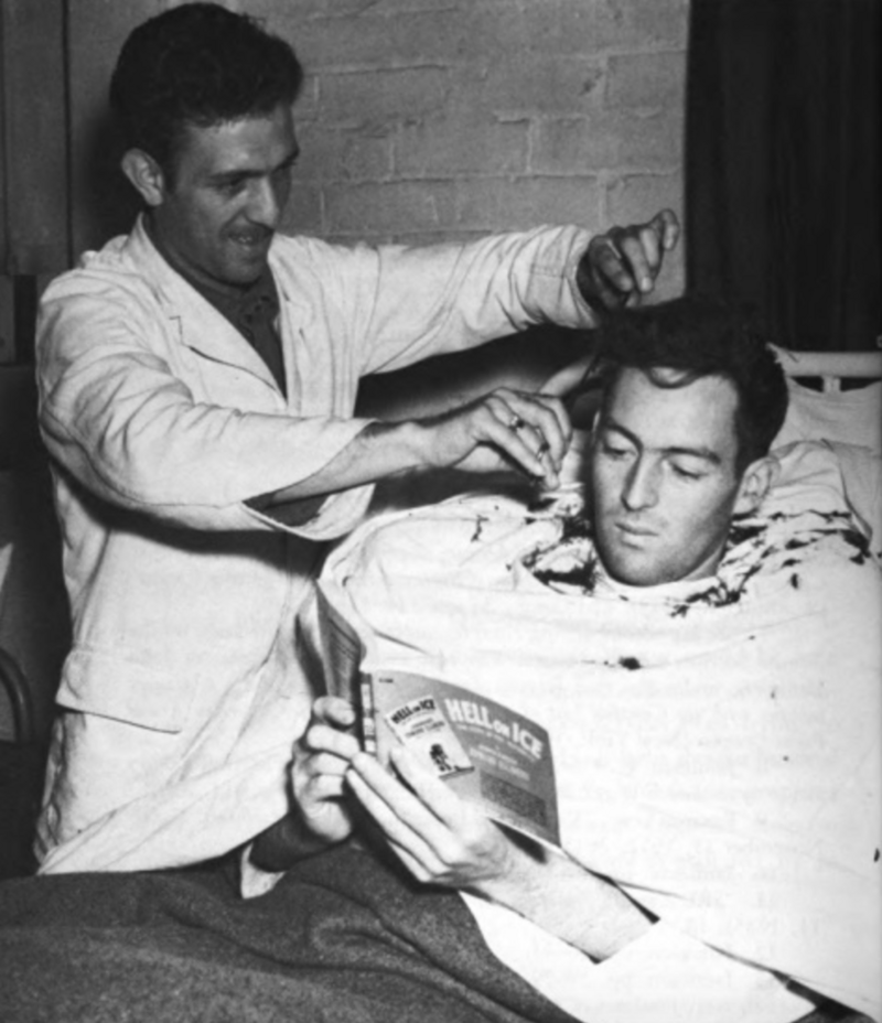 A soldier reads an Armed Services Edition of Edward Ellsberg's <em>Hell On Ice</em> while getting a haircut.