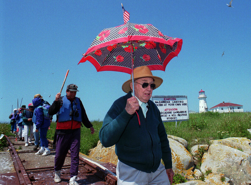 Barna Norton leading a group of birdwatchers on Machias Seal Island in 1998, at the age of 83. Notice the declaration of sovereignty atop his umbrella. 