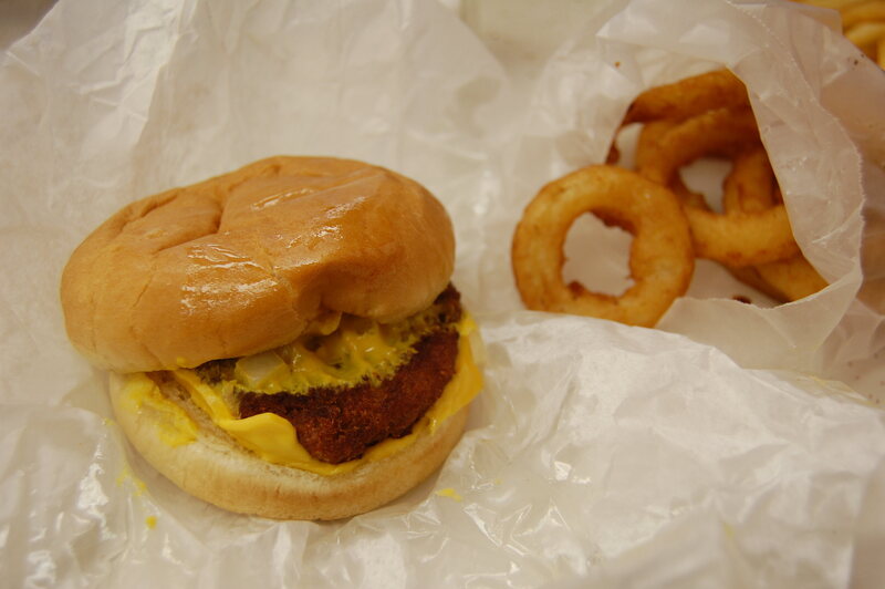 A slugburger with cheese and a side of onion rings.
