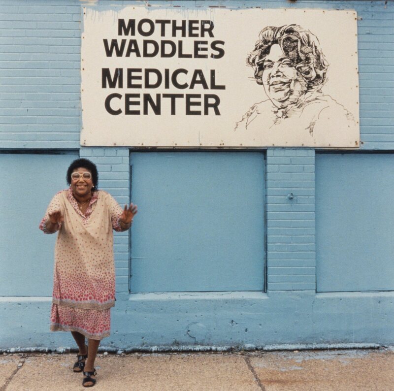 Waddles in front of the health center she founded.