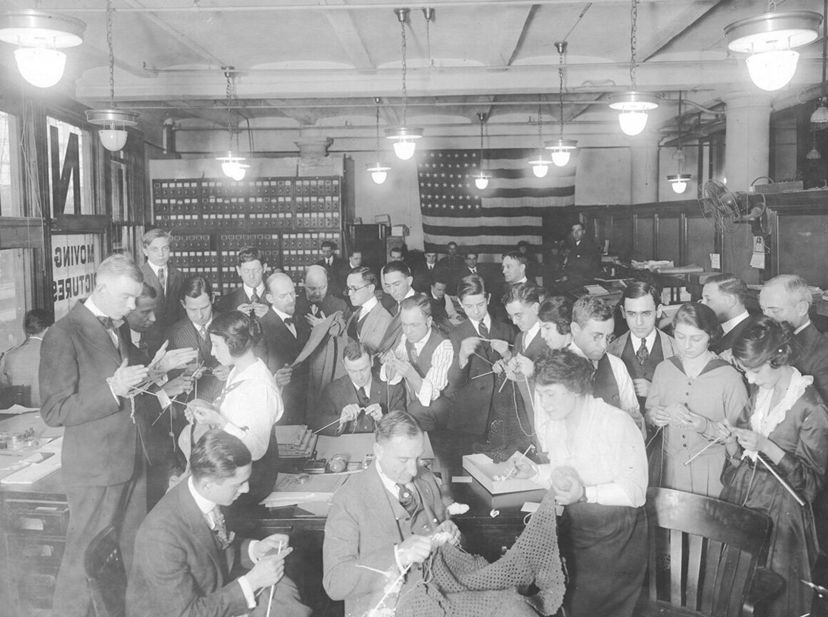 Male employees of the Universal Motion Picture Company knit during lunch hour, under the guidance of female stenographers.