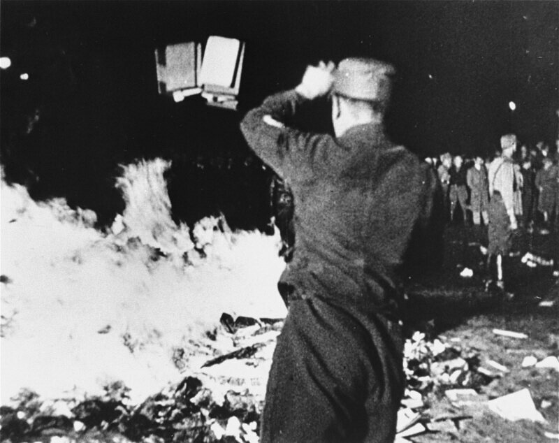 A member of the paramilitary Nazi Sturmabteilung throws confiscated books into a bonfire during the public burning of "un-German" books in Berlin in 1933.