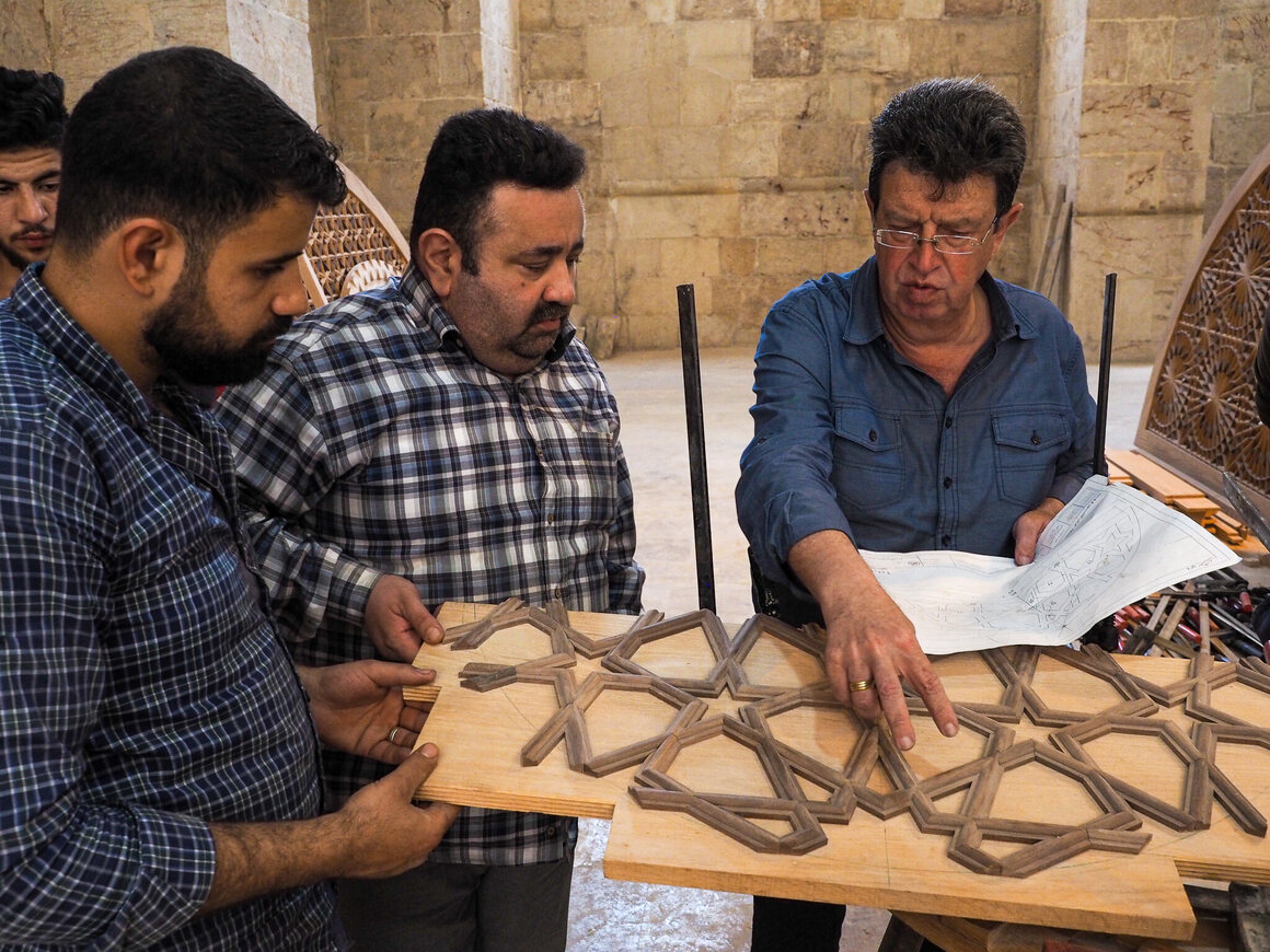 Architect Sakher Oulabi (right) and woodworker Ahmad Khattab (center) discuss restoration of the Great Mosque’s destroyed timbers.