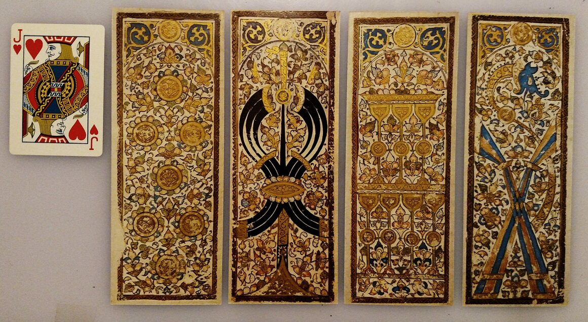 A reproduction of some Mamluk cards (coins, scimitars, cups, and polo sticks) next to a modern card for size.