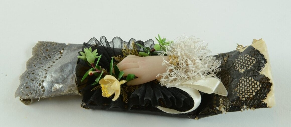 Some wrappings included wax figurines, such as this hand clutching a fabric flower.
