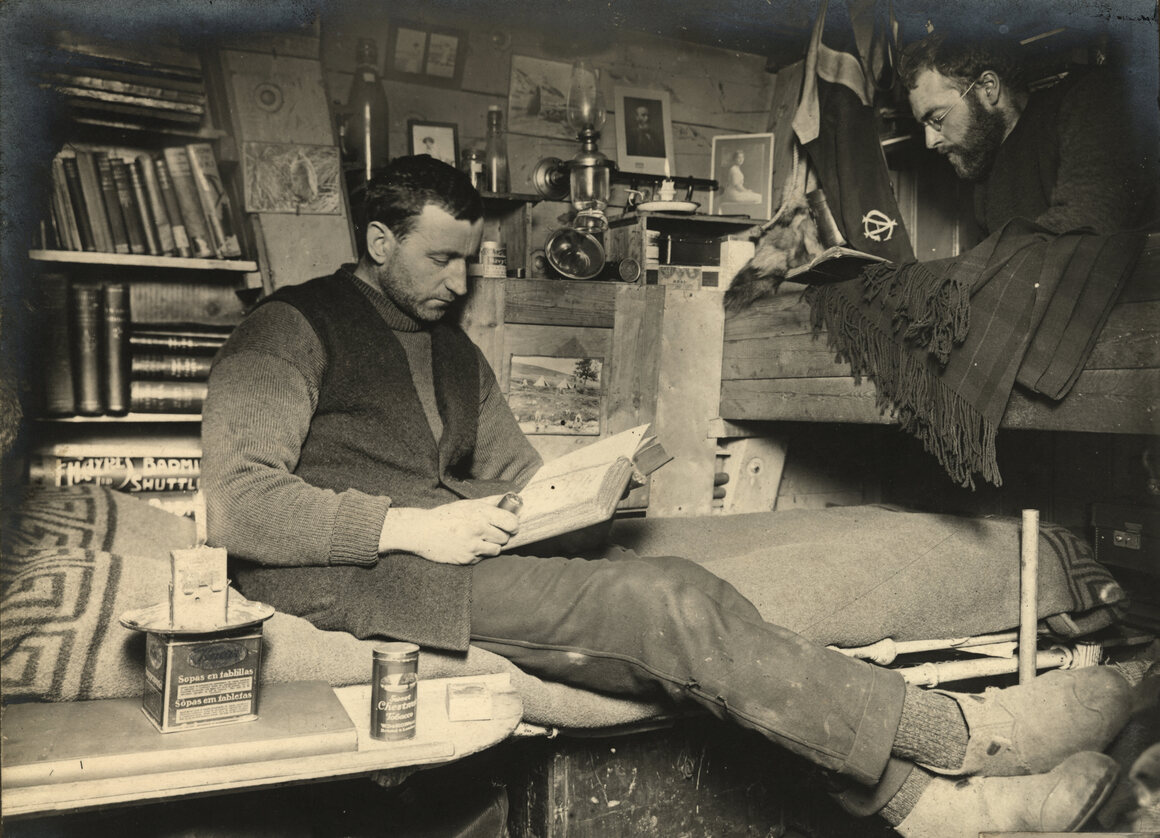 Biologist Robert Clark and geologist James Wordie cozied up with books in their cabin on <em>Endurance</em>.