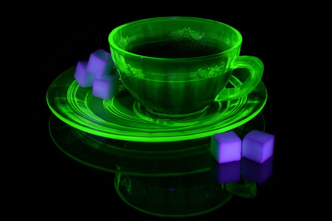 A uranium glass teacup and saucer under ultraviolet light.