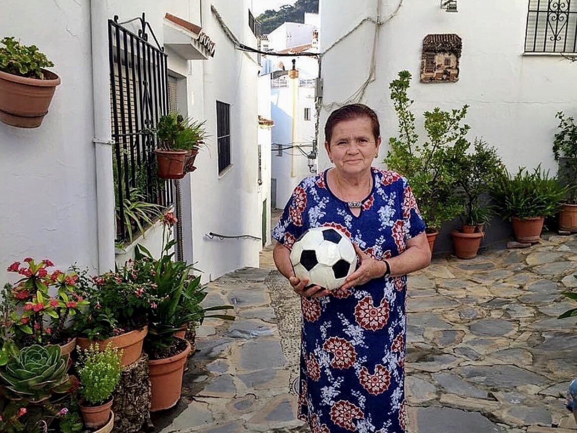 Antonia Herrera sostiene un balón de fútbol de cerámica para Miguel Moreno, uno de varios esparcidos por el pueblo.