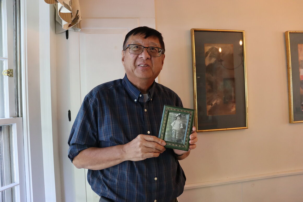 Stephen holds a photo of his mother, in his home.